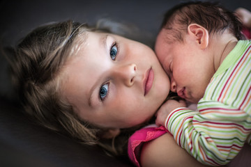 Little girl hugs her newborn sleeping sister