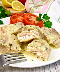 Fish stew in creamy sauce with tomatoes in plate on board