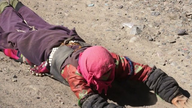 Tibetan pilgrims stretches during kora around Mapam Yumco lake.