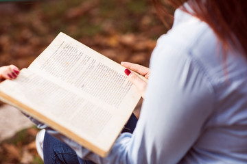 Redhead girl sitting on stairs and reading a book