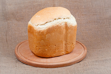Bread on a wooden board on a background of the canvas.