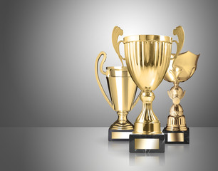 three different kind of golden trophies on gray background