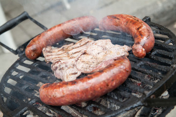 Grilling sausages and chop on barbecue grill