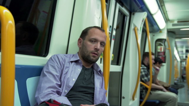 Sad man looking to the camer and riding on metro, steadycam shot