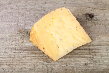 piece hard cheese with herbs on an old wooden table
