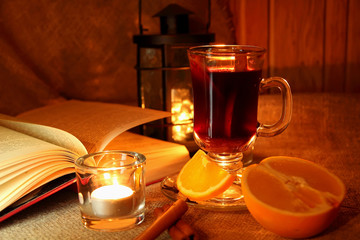 Hot mulled wine in the cup and open book.