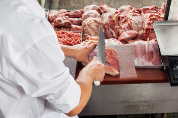 Cropped Image Of Male Butcher Cutting Meat