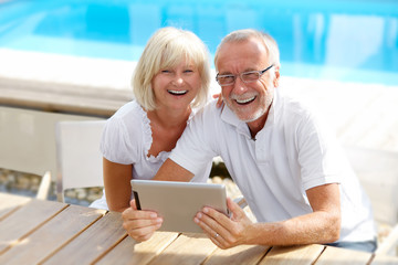 Different aged couple with a tablet pc outside