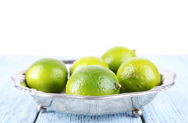Fresh juicy limes on plate on wooden background