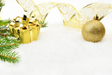 Golden christmas baubles with and needles fir and ribbon on snow