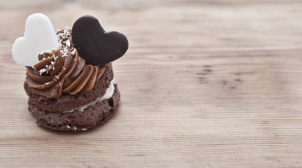 A cupcake on a table with two chocolate hearts