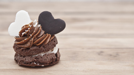 A cupcake on a table with two chocolate hearts