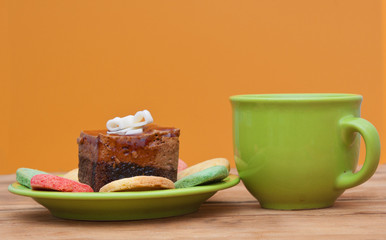 tea cup with colorful cookies, and  brown muffin on table