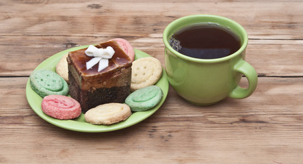 tea cup with colorful cookies, and  brown muffin on table