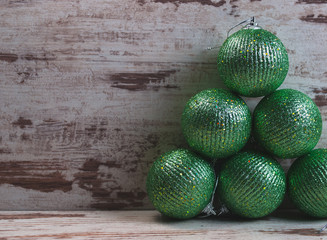 Green christmas balls in a stack over wooden background