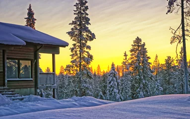 Fototapeten Wooden cottage house in Lapland Finland at winter sunset © Roman Babakin
