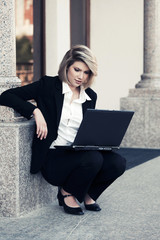 Young business woman with laptop at office building