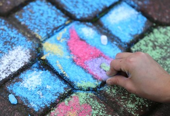 hand of a child who draws with chalk on the road