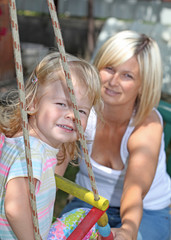 Smiling mother and daughter having fun on playground