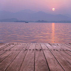plank board with lake in sunset as background