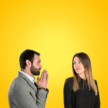 Men pleading at his girlfriend over yellow background