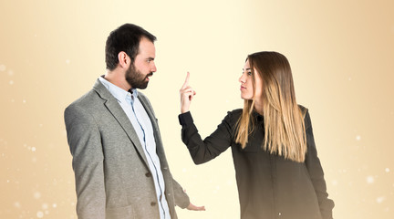 Girl doing the horn sign at her boyfriend over gloss background