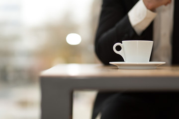 Kaffeetasse im Fokus auf Tisch, vor Geschäftsmann 