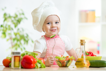 child girl in cook hat eating vegetables