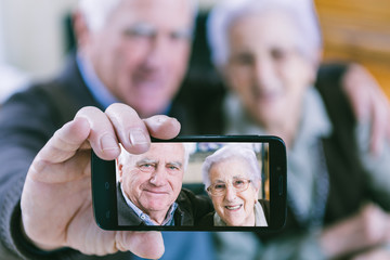 Senior couple showing self portrait photo on smartphone - 73463772