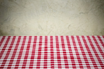 Rot-weiß kariertes Tischtuch vor rustikaler Wand