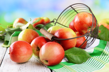 Sweet apples in wicker basket on table on bright background