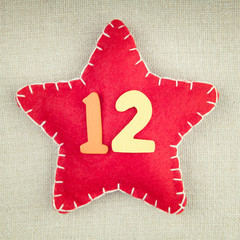 Red star with wooden number 12 on vintage fabric background