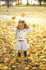 Happy Little Girl Throwing Autumn Fall Leaves In The Air Outdoor