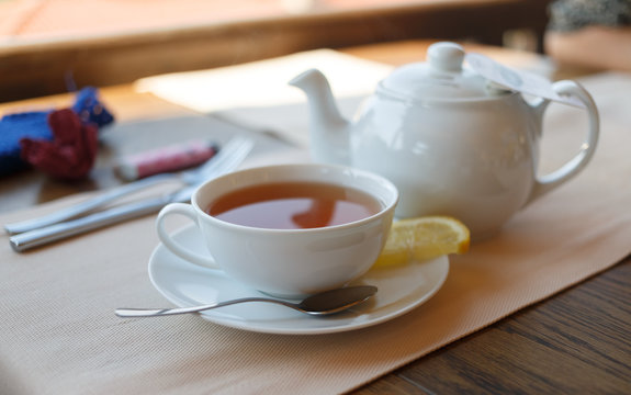 Cup of tea with lemon and teapot