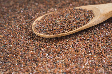 flax seeds with a wooden spoon on burlap background