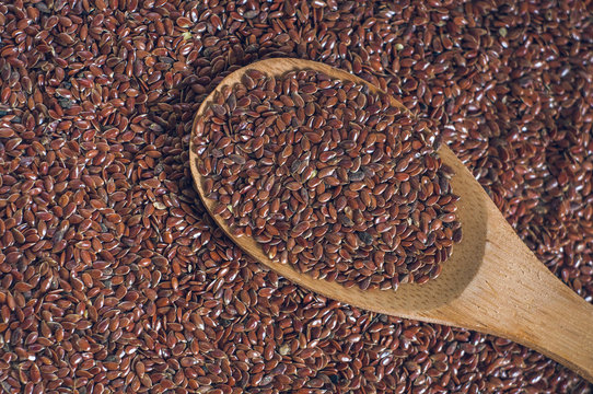 flax seeds with a wooden spoon on burlap background