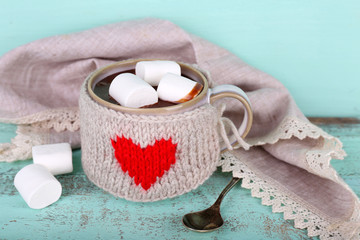 Cup of tasty hot cocoa, on wooden table, on color background