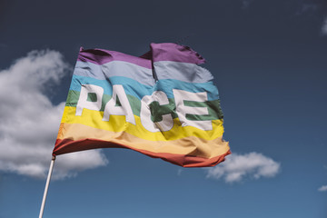 Pace, Peace Flag waving against blue sky
