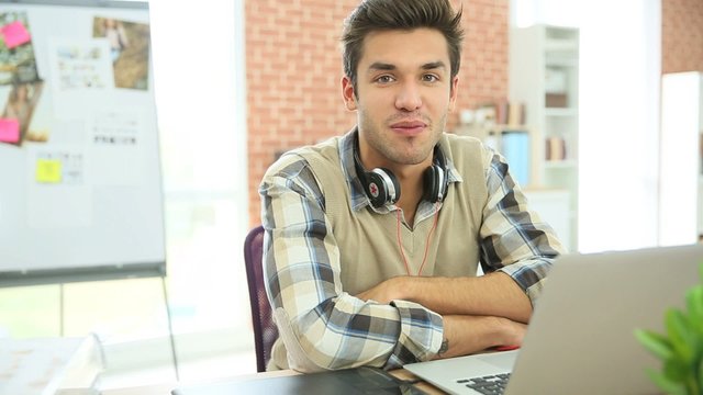 Young man in office talking to camera 