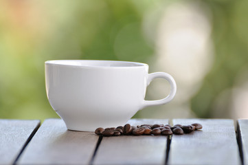 Coffee seeds with white cup and nice bokeh blur background.
