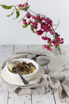 pasta with pioppini mushrooms on table with branch of berries