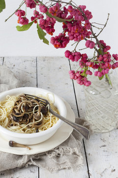 pasta with pioppini mushrooms on table with branch of berries