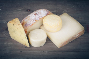 Various types of cheese on a wooden background. tinted