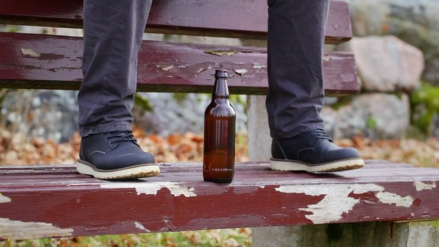 Beer bottle at a man's legs on the bench