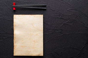 Chopsticks and restaurant menu concept on black rock