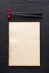 Chopsticks and restaurant menu concept on black rock - 73486324