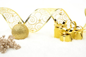 Golden christmas gifts,baubles ribbon and rowan on snow