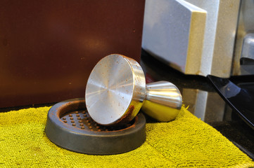 Single coffee-tamper set on yellow cloth.