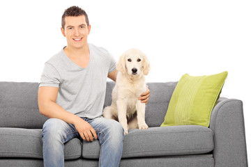 Young guy sitting on a sofa with a cute puppy