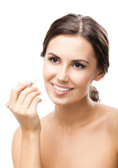 Smiling woman applying concealer on face, isolated